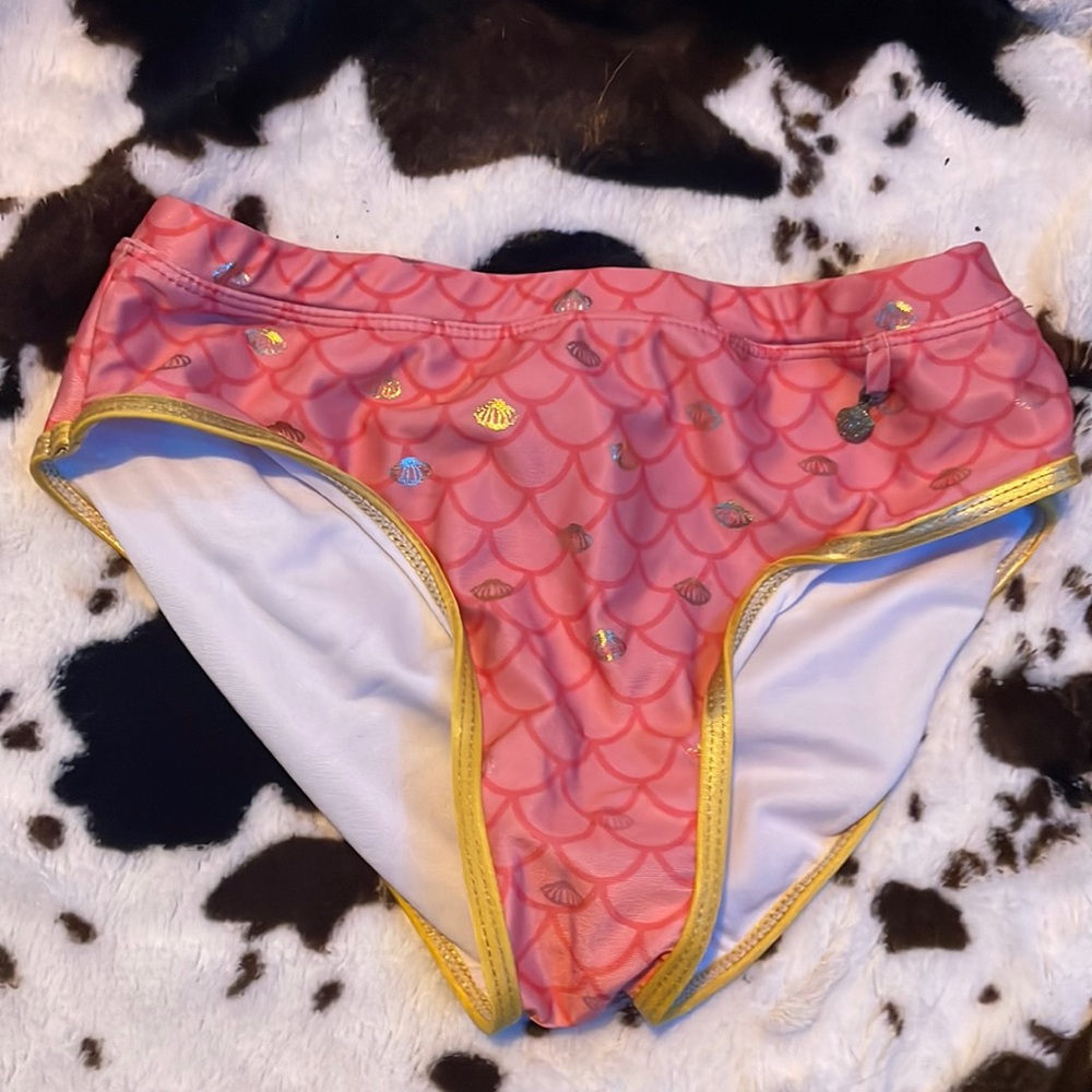 a pink and gold two piece bathing suit with a sea shell charm
